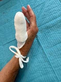 Hand with bandaged finger on blue sheet
