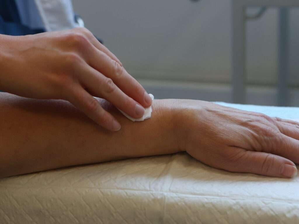 Hand cleaning forearm with a wipe.