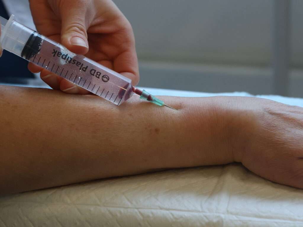 Syringe drawing blood from an arm