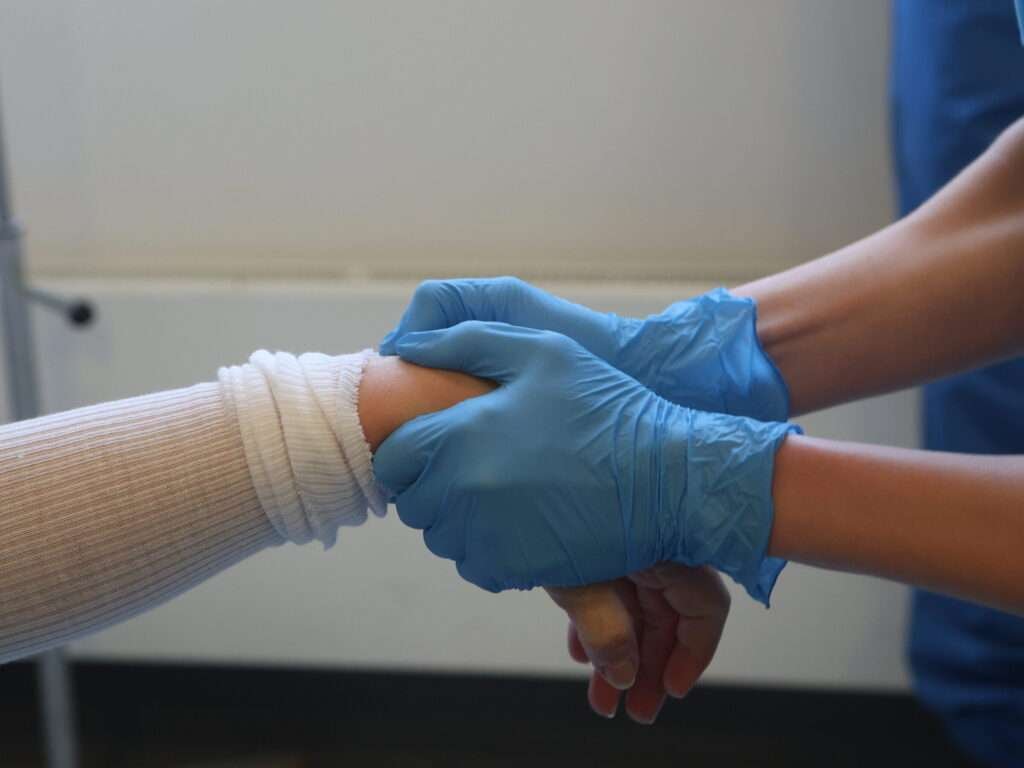 Hands in blue gloves bandage an arm