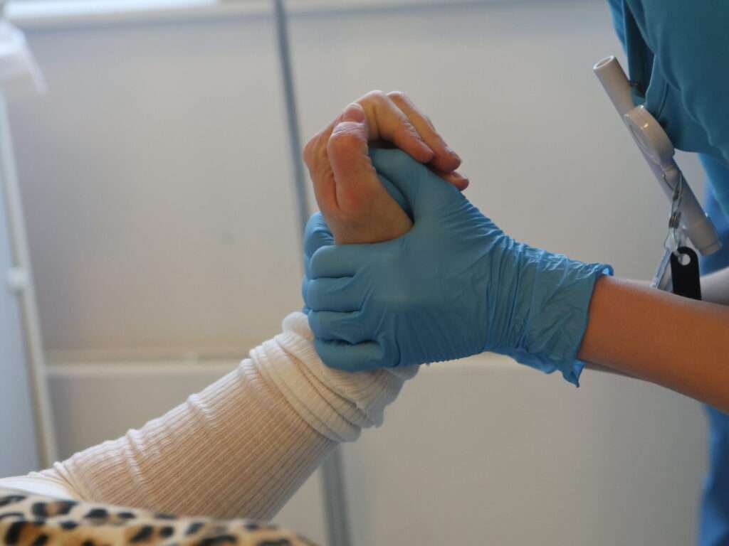 Nurse holding a patient's hand gently.